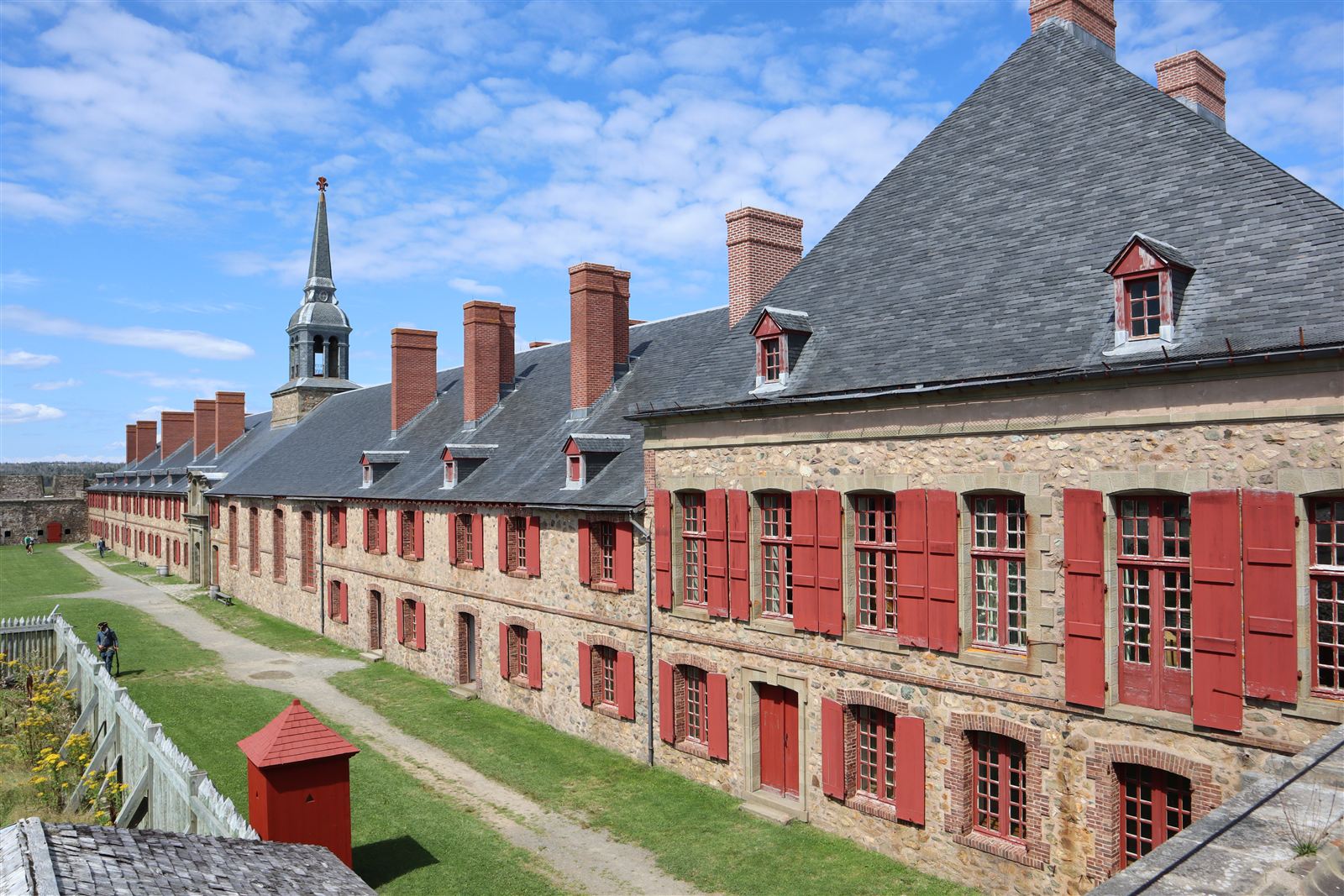 The stone King’s Bastion barracks at the Fortress of Louisbourg, with red shutters, slate roof and chapel spire